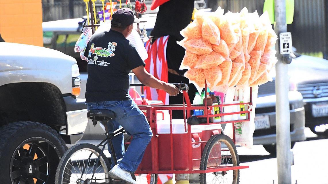 A street vendor works the busy intersection of Tulare and Cedar avenues in Fresno on March 31, 2021.