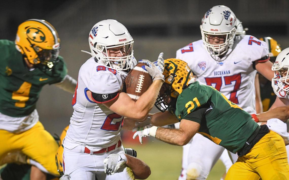 Buchanan’s Caden Rodgers, left, pushes through for a few yards against Kingsburg at Kingsburg High on Friday, Aug. 20, 2021.