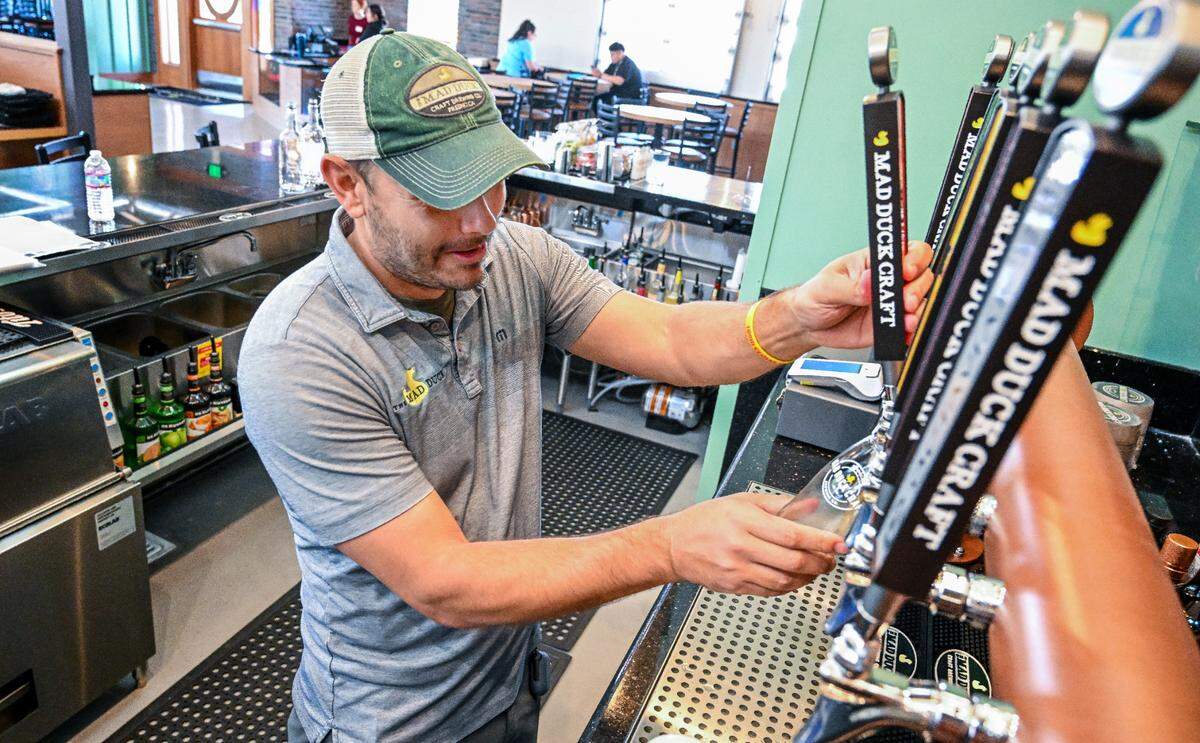 Alex Costa, one of the owners of Mad Duck, pulls a tap for a draft beer at the Fresno brewery and restaurant’s fourth location at Copper and Maple in north Fresno on Friday, April 12, 2024.