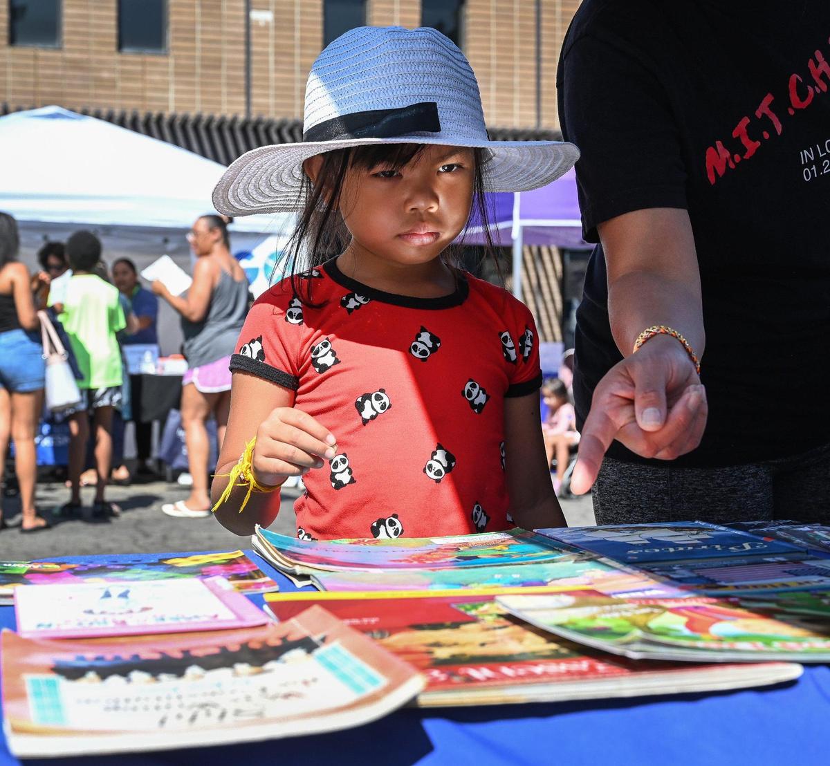 Madison Mekeara, 7, of Fresno decides on a book to take during a backpack and school supplies giveaway for the new school year at United Way Fresno and Madera Counties in Fresno on Saturday, Aug. 6, 2022.