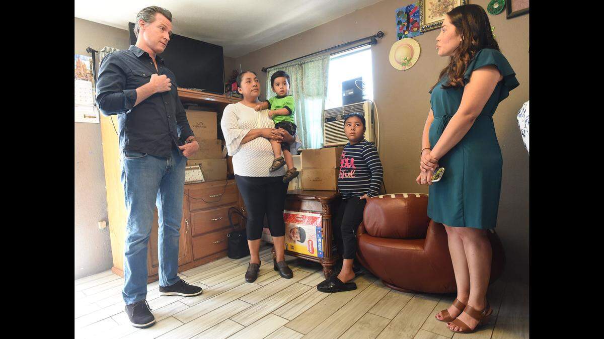 Gov. Gavin Newsom listens to a comment by Sanger-area resident Carolina Garcia, holding her 1-year-old son Alex, with daughter, Natalia, as translated by Veronica Garibay, co-executive director, Leadership Counsel for Justice and Accountability. Newsom signed into law SB 200, which creates the Safe and Affordable Drinking Water Fund, Wednesday July 24, 2019.