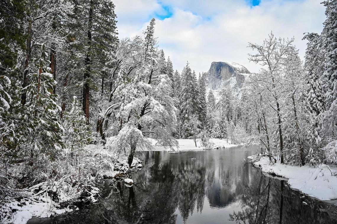 Snow covers the trees and Half Dome in the distance as seen from Sentinel Bridge in Yosemite Valley on Wednesday, Dec. 15, 2021, following a snowstorm the day before.