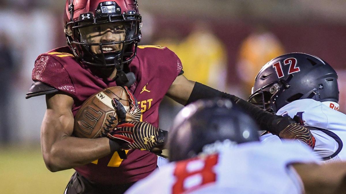Clovis West’s Jonavon Darrington, left, looks for an opening around the Memorial defense while taking the ball to the outside during their Central Section semifinal playoff game at Lamonica Stadium in Clovis on Friday, Nov. 18, 2022.