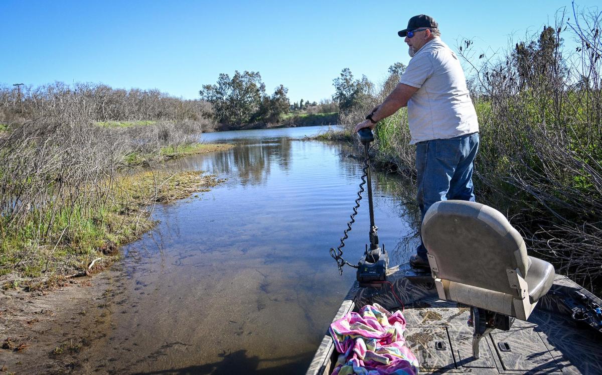 El guía de pesca Louis Moosios navega con su barca por un canal poco profundo del río San Joaquín antes de entrar en Milburn Pond, al norte de Fresno, el jueves 14 de marzo de 2024.