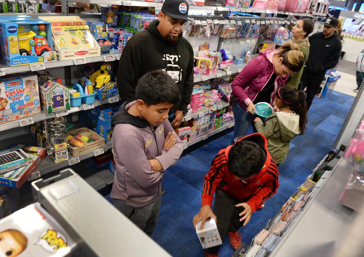 Josue Salazar and his wife Adriana of Kerman watch as their children examine the toy aisle at Best Buy during the Black Friday shopping event at River Park in Fresno on Friday, Nov. 23, 2018.