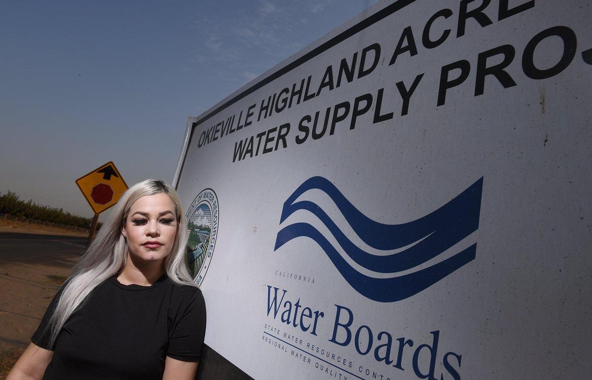 Mayra Marquez stands outside the fenced and gated water well, Friday, Aug. 13, 2021 in Tulare County’s Okieville.