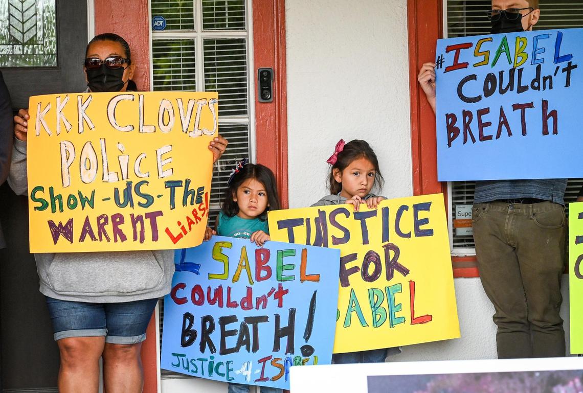 Supporters of Isabel De La Torre hold signs during a news conference held by attorneys from the Gonzalez and Flores law firm to announce a lawsuit filed against the Clovis Police Department in the death of De La Torre earlier this year, outside the law office of attorney Kevin Little in Fresno on Friday, June 17, 2022.