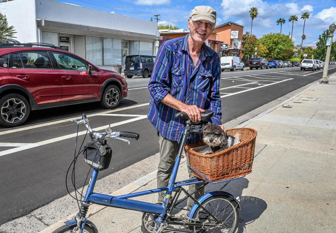 Chris Eacock, of Tower Velo, stands with his bike and dog Tuxedo near the new bike lane layout in front of his repair shop on Van Ness Avenue in Fresno on Tuesday, Sept. 20, 2022. Although Eacock supports the new bike lane layout meant to protect cyclists, he recognizes that people have been confused about it.
