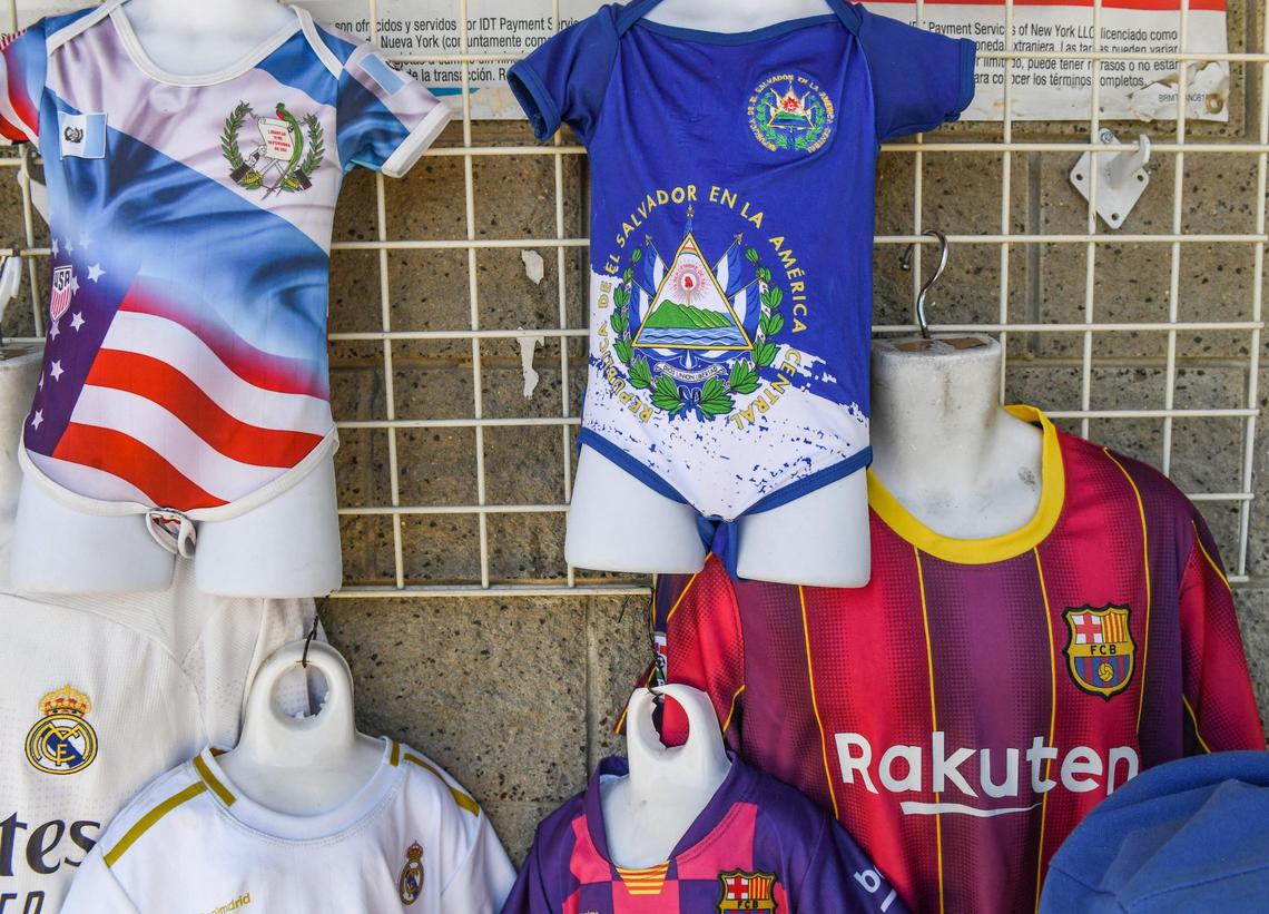 A Salvadoran flag-themed baby onesie, center, is displayed outside the Recuerdos de Mi Pais (Memories of my Country) shop in Mendota on Thursday, June 10, 2021.