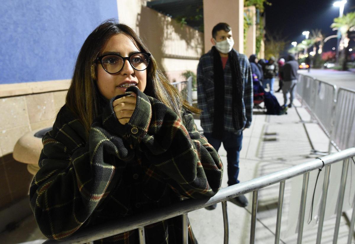 Sienna Vasquez tries to keep warm as she and friend Jeremiah Dunlap, center, waiting since 9 p.m. Thanksgiving Day, at the head of the line at Best Buy at River Park shopping center, at 4:30 a.m., for the 5 a.m. opening. They were in line in hopes of getting an electronic game for Dunlap.