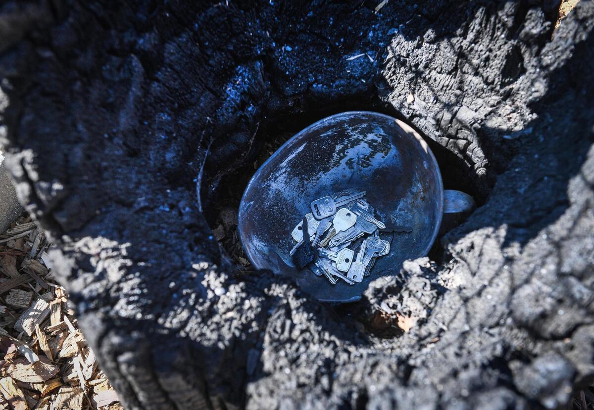 Old keys are thrown into a charred bowl inside a burned out stump by Creek Fire survivors as a symbolic gesture to move past the pain of the devastation and work toward healing during the Creek Fire Recovery Collaborative’s One-Year-Stronger event in Shaver Lake on Saturday, Sept. 4, 2021.