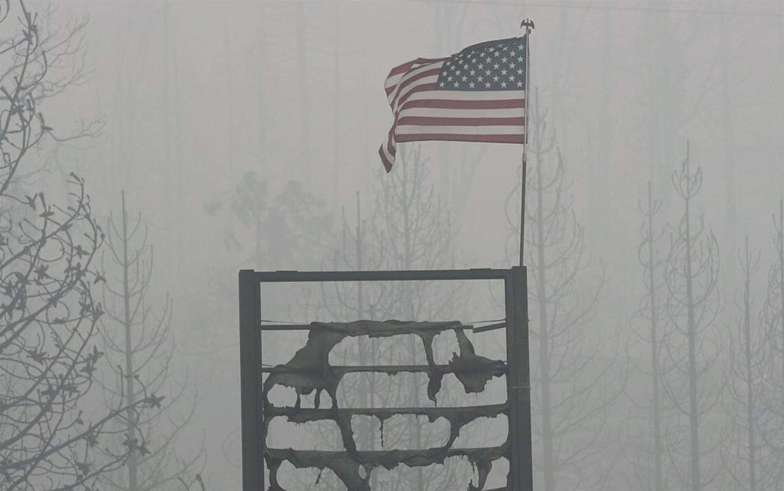 A flag flies in the smoky air above the melted gas station sign at the burned Cressman’s General Store, a victim of the Creek Fire, on Highway 168 below Shaver Lake Saturday, Sept. 12, 2020. Firefighters raised the flag Friday while taking a moment to honor 9/11.