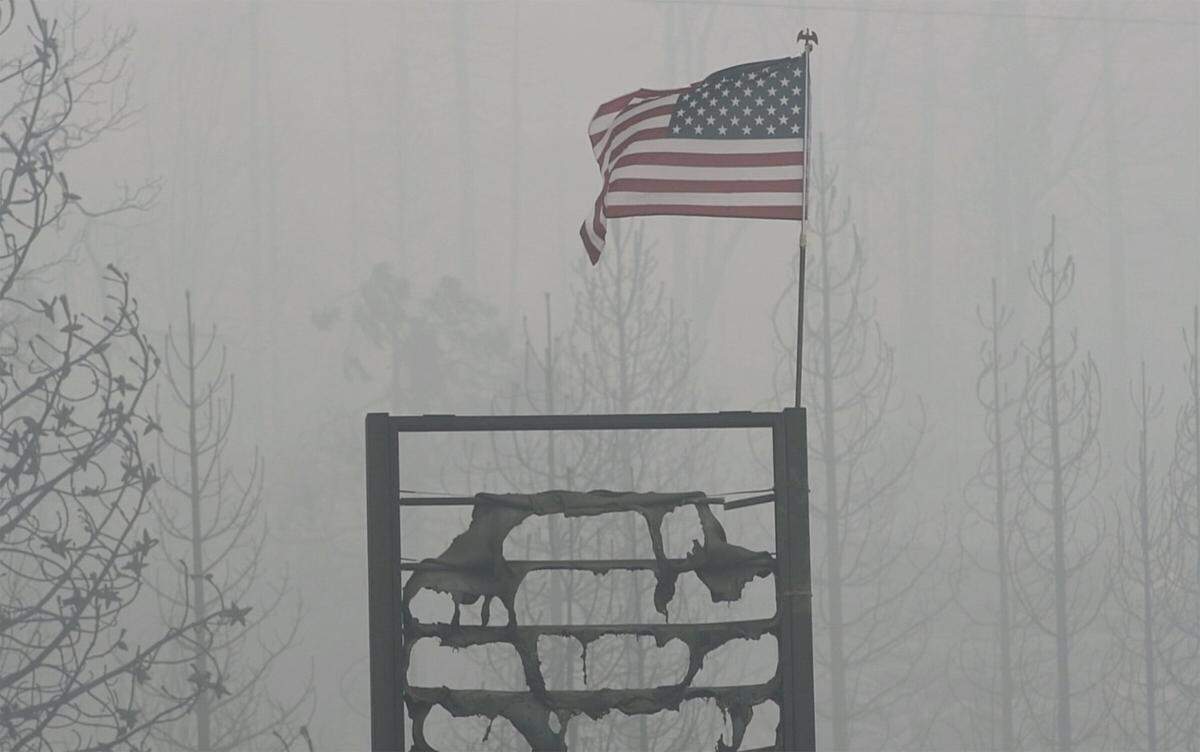 A flag flies in the smoky air above the melted gas station sign at the burned Cressman’s General Store, a victim of the Creek Fire, on Highway 168 below Shaver Lake Saturday, Sept. 12, 2020. Firefighters raised the flag Friday while taking a moment to honor 9/11.