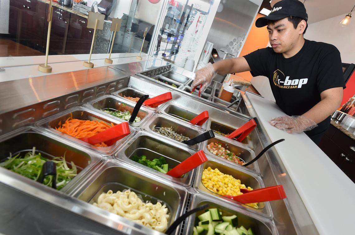 Timmy Ros, assistant manager at K-bop Korean Rice Bar, prepares an assortment of toppings for the Bibimbap, a Korean mixed rice bowl.