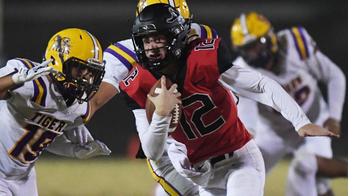 Hanford quarterback Cayden Muir runs the ball in for a touchdown with Lemoore’s Gio Quintero chasing at the left in the Milk Can Game Friday night, Oct. 29, 2021 in Hanford. Hanford defeated Lemoore 42-0.
