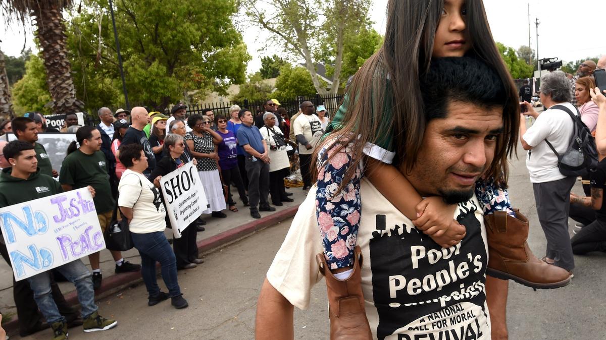 A member of the California Poor People’s Campaign, Miguel Torres, carries his 4-year-old daughter, Jimena Torres, during the rally near the Poverello House, Monday, April 8, 2019, to raise awareness on poverty.