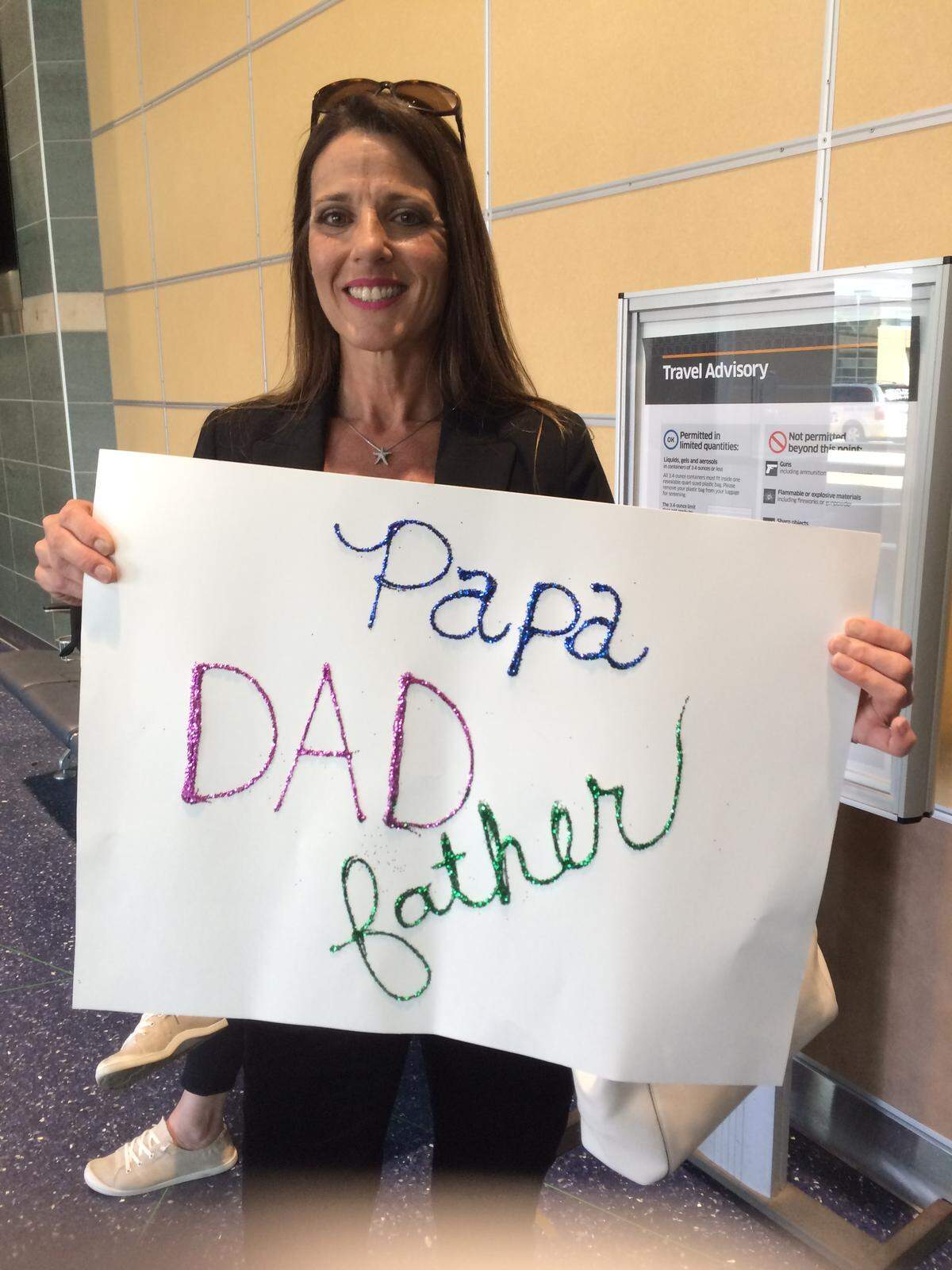 Tiffany Dow holding a sign she made to greet her dad Doug Davidian after he flew to Kansas City, Missouri, earlier this year to meet her.