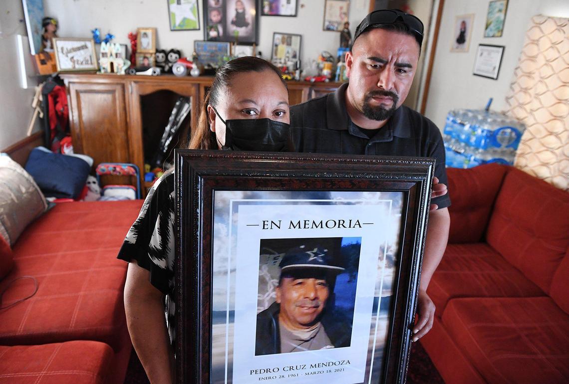 Claudia Medina, left, with her son, Juan Cruz, right, holds a framed photo of her husband, Pedro Cruz Mendoza, who died from COVID-19, during an interview at the family’s home in Lemoore on April 6, 2021 .