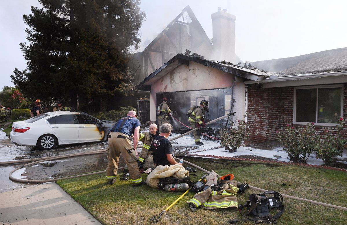 Fresno Fire Department crews continue to work the scene of a fire that quickly spread from one home to another Monday, July 26, 2021, in northwest Fresno, California.