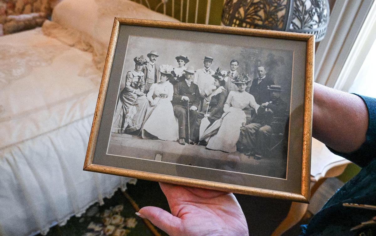 Tour guide Debbie Unger of the Fresno County Historical Society shows a photograph of M. Theo Kearney seated at center among prominent society members of his day, while touring the Kearney Mansion, also known as the superintendent’s lodge.