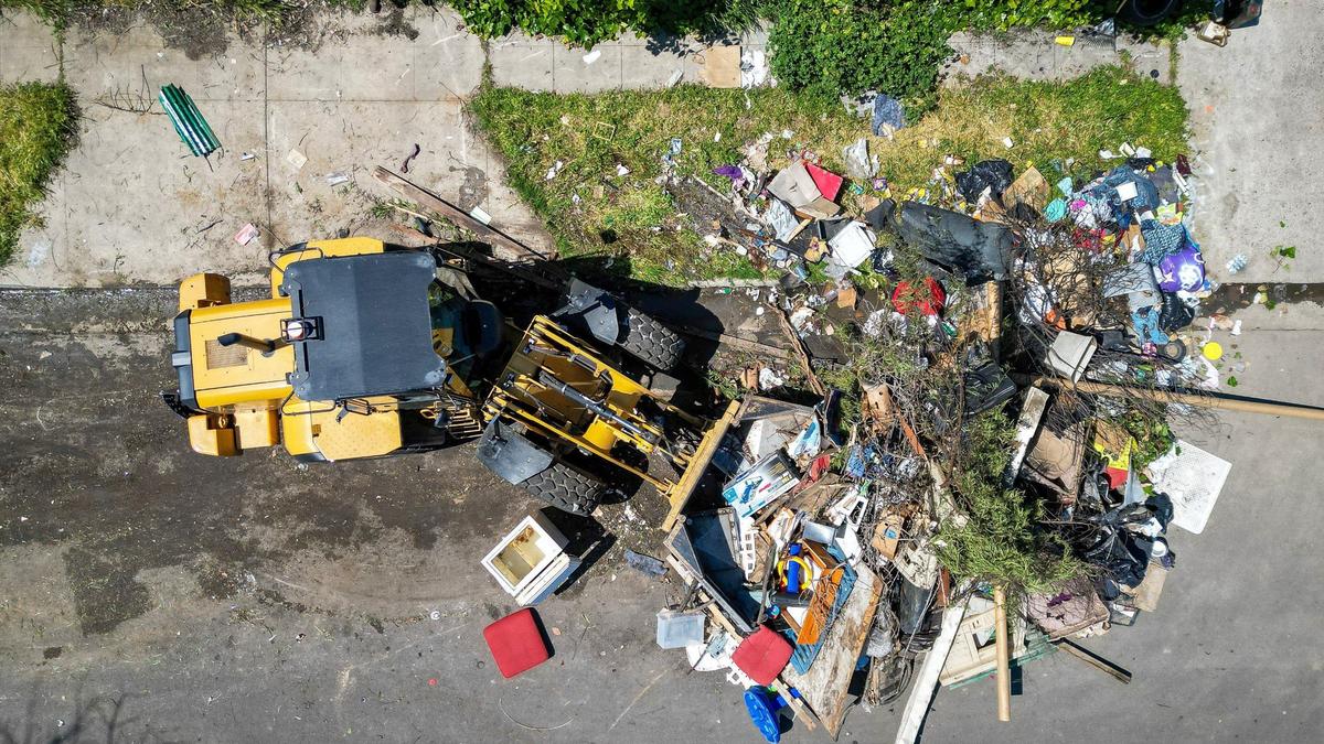 A city worker uses “the Claw” frontloader to scoop up residential trash left out on a street in southeast Fresno during Operation Cleanup in Fresno on Monday, April 8, 2024.