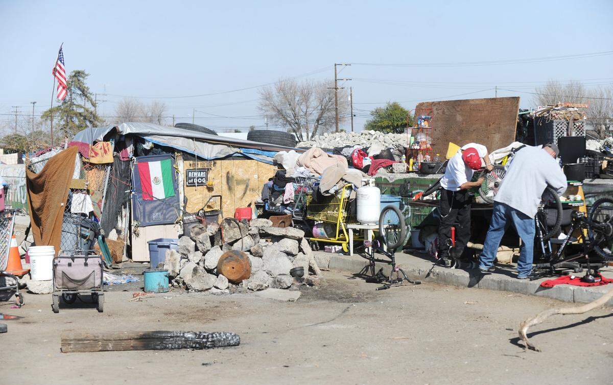 Two men are repairing bicycles on the corner of Mercey Springs Road and G Street Wednesday afternoon, February 5, 2014.