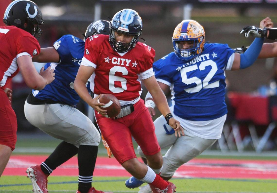 Bullard quarterback Roland Russo, center, scramble after being pressured by County at the City/County All-Star football game held at McLane High’s stadium Friday night, June 17, 2022 in Fresno. The game ended 21-21.