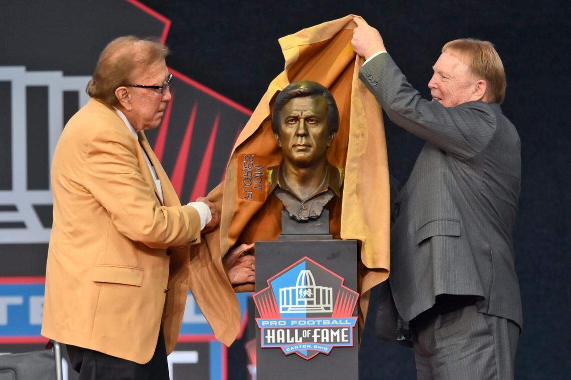 Tom Flores, a member of the Pro Football Hall of Fame Class of 2021, left, and his presenter Las Vegas Raiders owner Mark Davis unveil Flores’ bust during the induction ceremony at the Pro Football Hall of Fame, Sunday, Aug. 8, 2021, in Canton, Ohio.