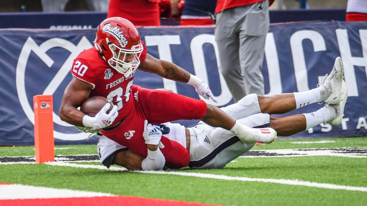 Fresno State’s Ronnie Rivers dives over the goal line for a touchdown while dragging Nevada’s Berdale Robins along with him during their game at Bulldog Stadium on Saturday, Oct. 23, 2021.