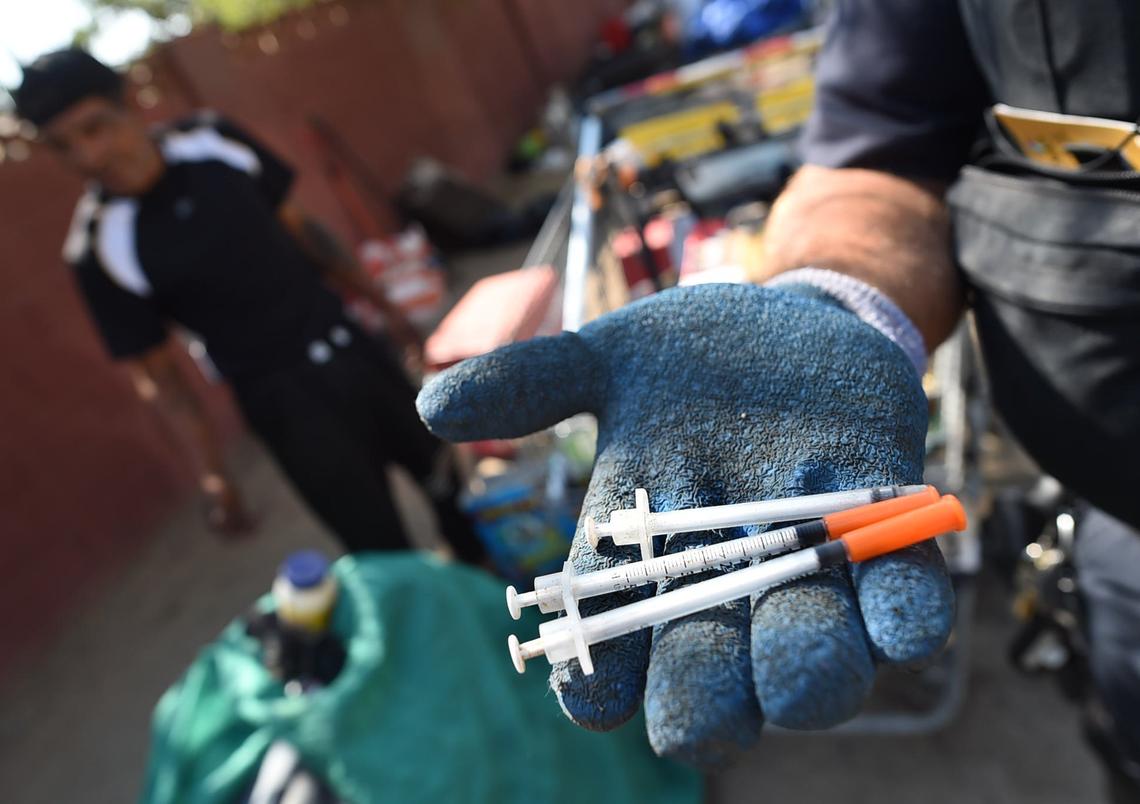 Officer Noel Perez shows hypodermic needles found at the camp of a homeless man during a cleanup of an alley on Wednesday morning, Aug. 14, 2018.