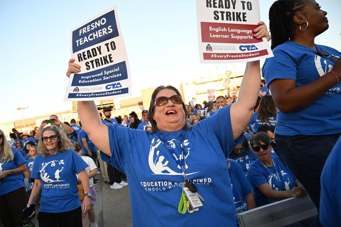 Kristina Ringo holds up two signs as she and over 3,000 members of Fresno Teachers Association met to vote for strike authorization at the Paul Paul Theater Wednesday evening, Oct. 18, 2023 in Fresno.