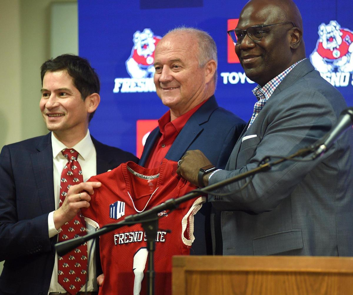 New Fresno State football coach Jeff Tedford, flanked by university President Saúl Jiménez-Sandoval, left, and athletics director Terry Tumey, right, hold up a jersey after a press conference Wednesday Dec. 8, 2021, introducing Tedford.