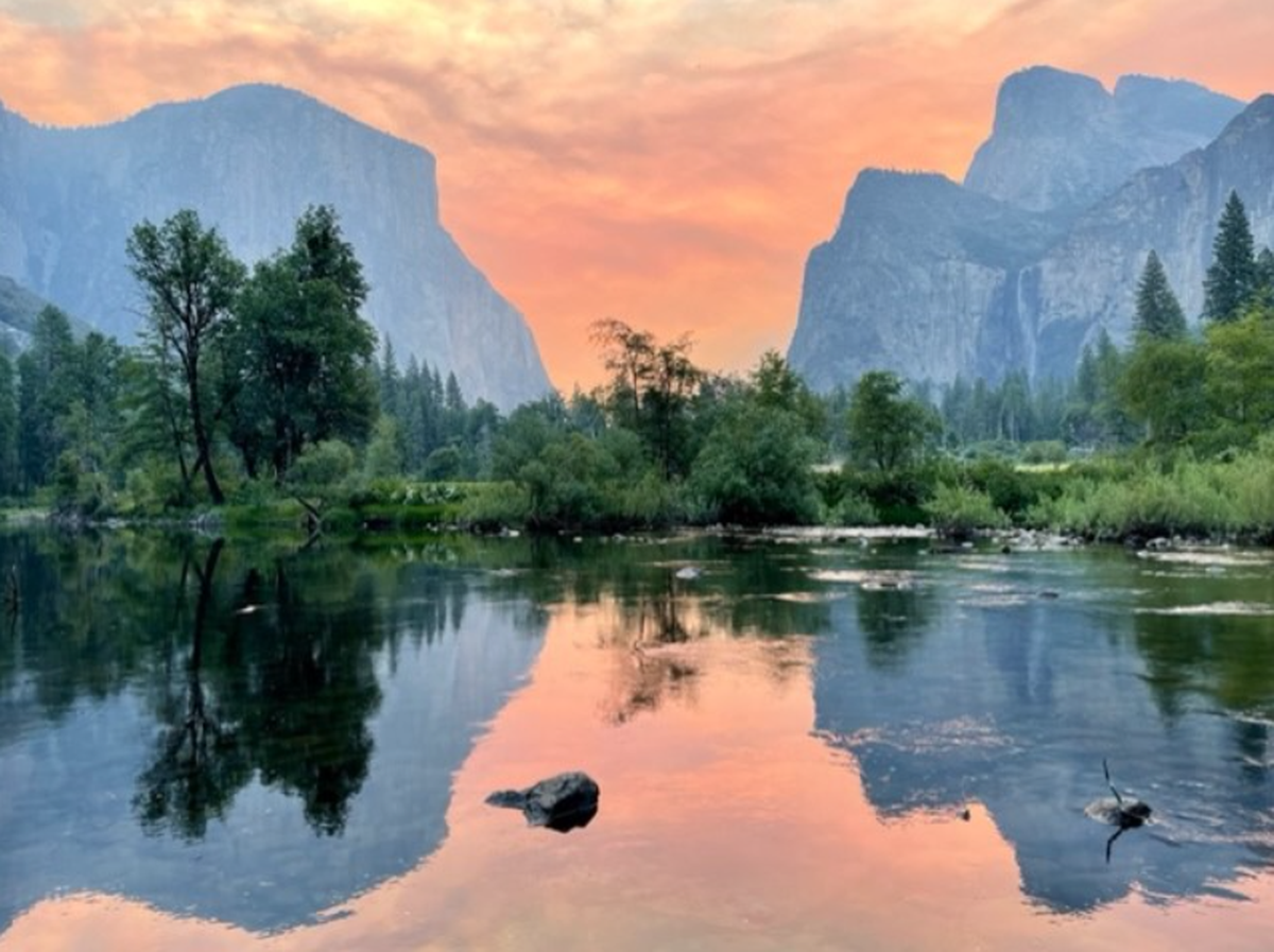Yosemite Valley View the morning of Saturday, July 9, 2022 showing pink sky conditions, the Merced River, Bridalveil Fall, and El Capitan as the Washburn fire burns near Mariposa Grove.