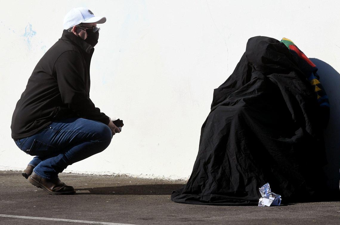 Volunteer Shawn Jenkins talks with a homeless person shrouded in black, who did not want to participate in the Point in Time count survey for the Fresno Madera Continuum of Care in the Tower District, Feb. 25, 2022.