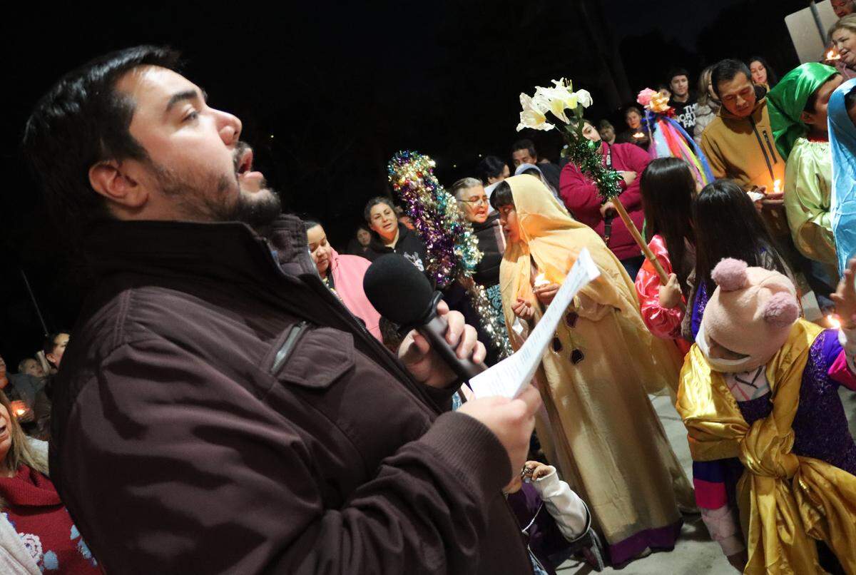 Father Agustín Carrillo leads a group in singing during the posada hosted by St. Anthony Mary Claret Church in southeast Fresno on Dec. 18, 2023.