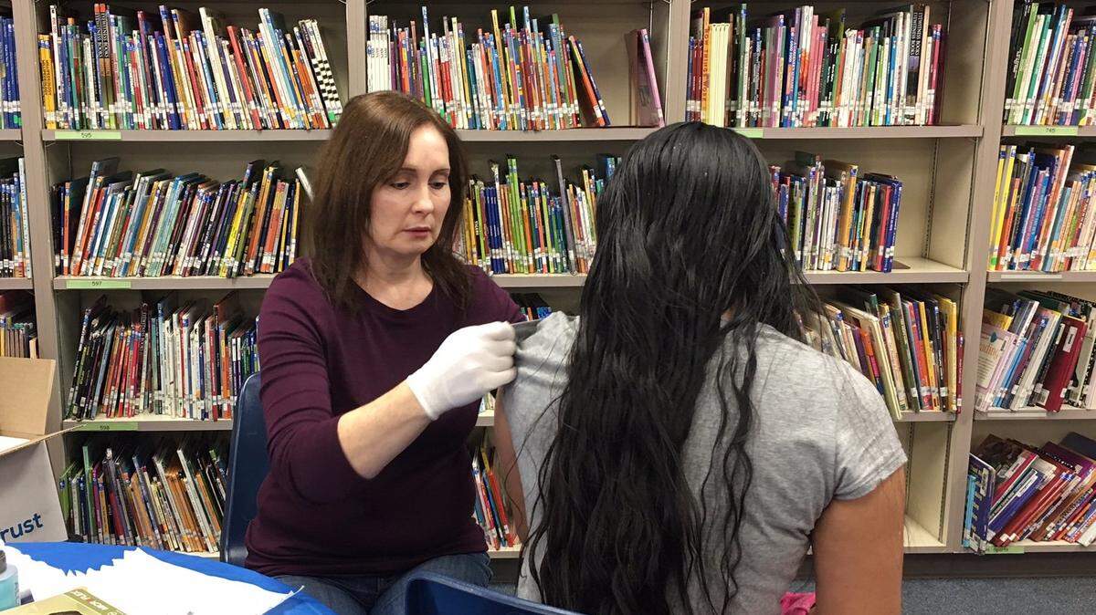 Dana Brantley, a nurse with the Merced County Department of Public Health, prepares to give a Tdap vaccination to a student at Stowell Elementary.