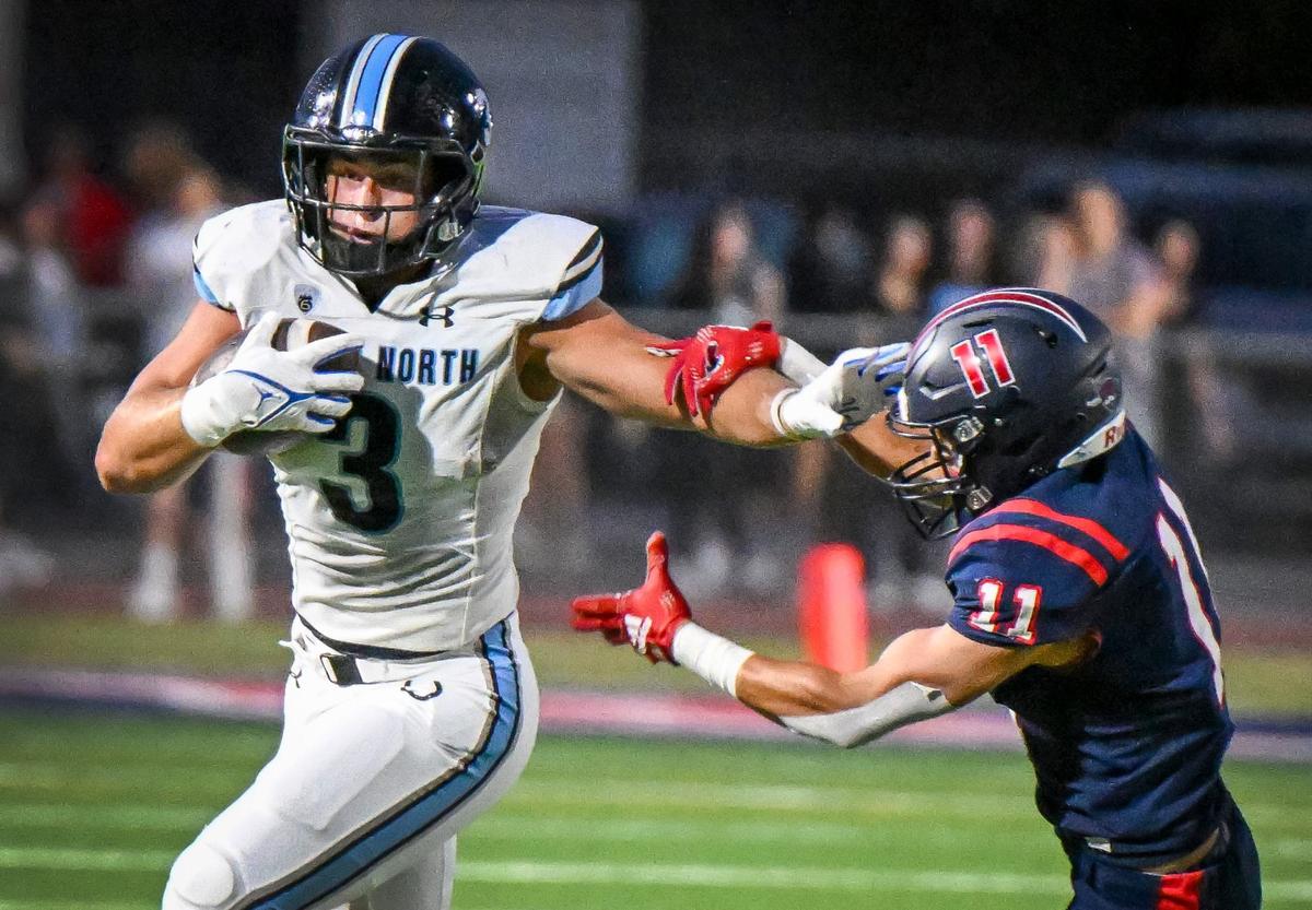 Clovis North running back Mckay Madsen, left, tries to stiff-arm his way past Memorial’s Luciano Delana on a run in the first half of their game at San Joaquin Memorial on Friday, Aug. 23, 2024.