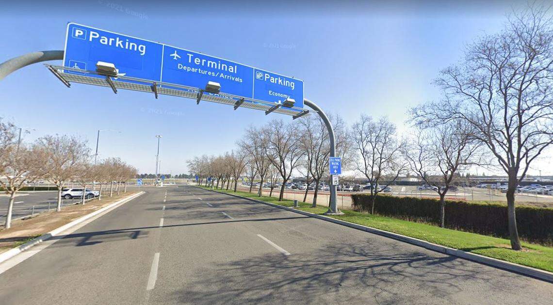 Signs over the entrance drive to the Fresno Yosemite International Airport terminal direct drivers to alternate parking lots, at right, built before construction began in September 2020 on a new parking structure.