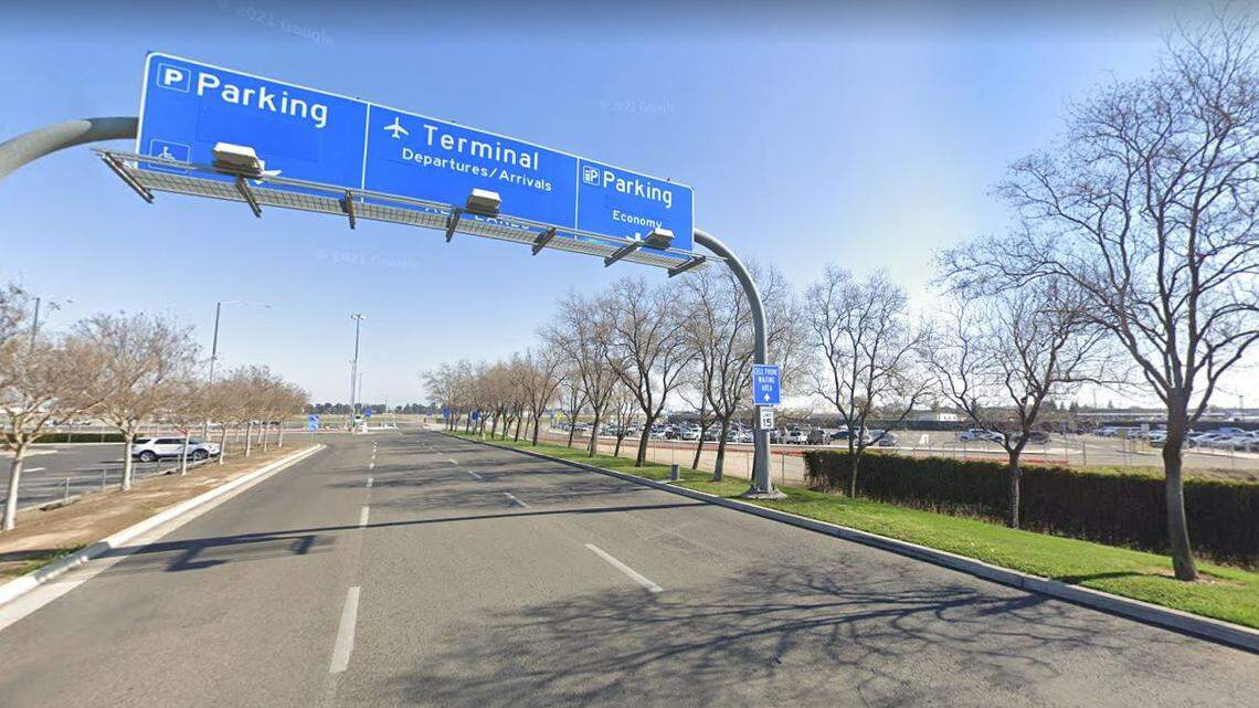 Signs over the entrance drive to the Fresno Yosemite International Airport terminal direct drivers to alternate parking lots, at right, built before construction began in September 2020 on a new parking structure.