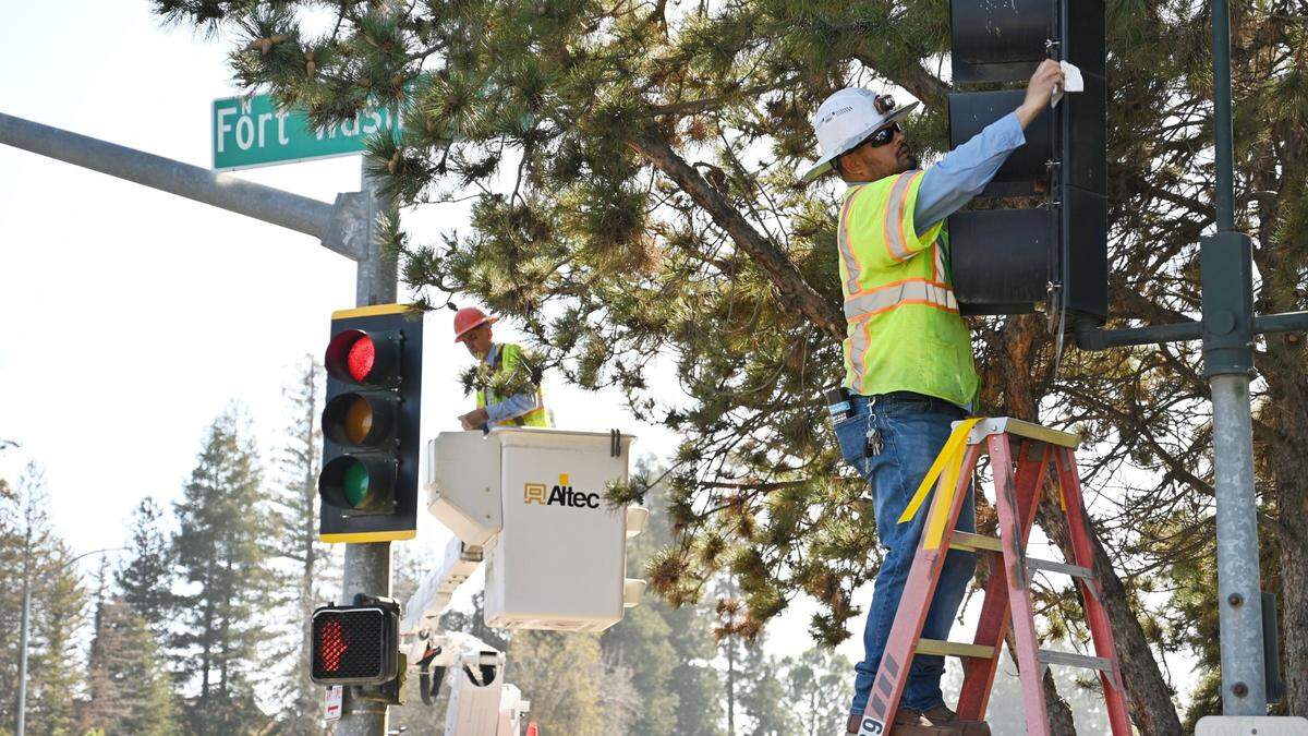 City workers installing reflective backplates to traffic signals at Friant and Ft Washington in north Fresno, California, on Thursday, Feb. 10, 2022.