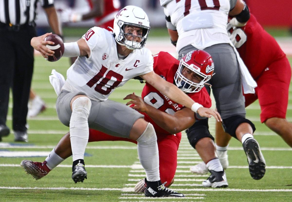 Washington State quarterback John Mateer, left, spins away of Fresno State’s Auckland Asiata, right, in third quarter action Saturday, Oct. 12, 2024 in Fresno. Washington State beat Fresno State 25-17.