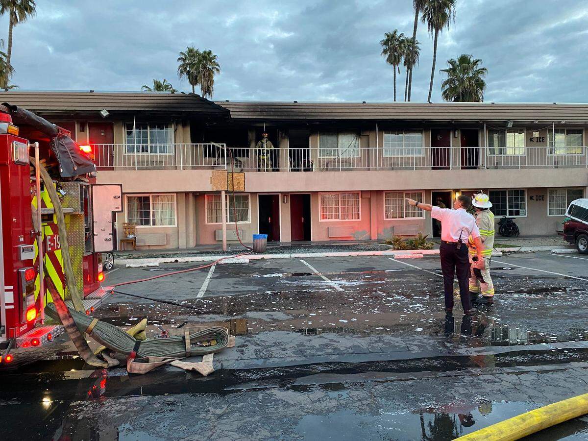 Firefighters survey the damage after a blaze at the former Days Inn in Fresno, California, on Tuesday, March 15, 2022.