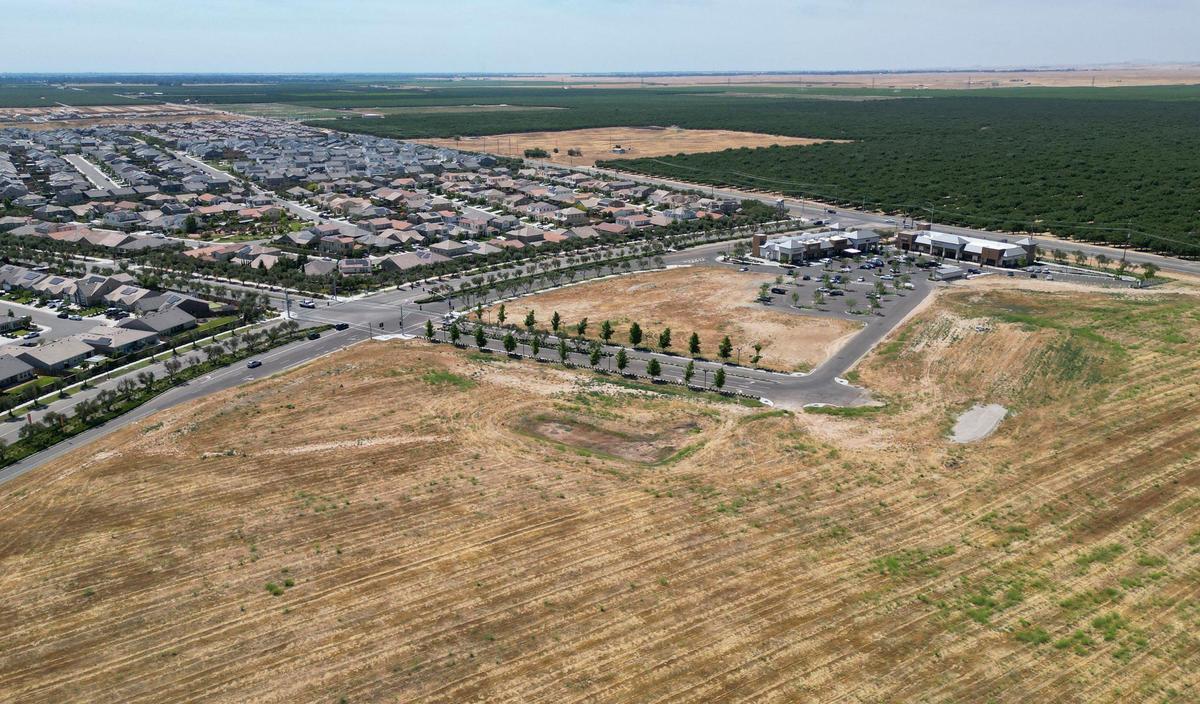 Empty fields, foreground, hint at the size that the Riverwalk retail area, middle right, may reach once completed, seen Wednesday, June 14, 2023. Riverstone homes are seen to the upper left.