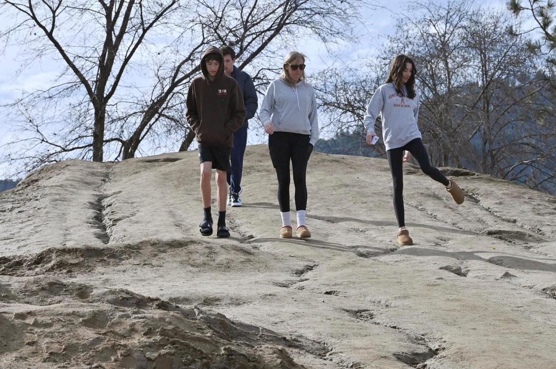 A family descend the 20-foot tall mound of dirt dubbed Mt. Chipotle in a parking lot Friday, Jan. 3, 2025 in Oakhurst. Located next to a new Chipotle Mexican Grill the mound may be permanently removed in a few days but until then the community of Oakhurst and others from around the Valley are enjoying the dirt made famous in social media posts.