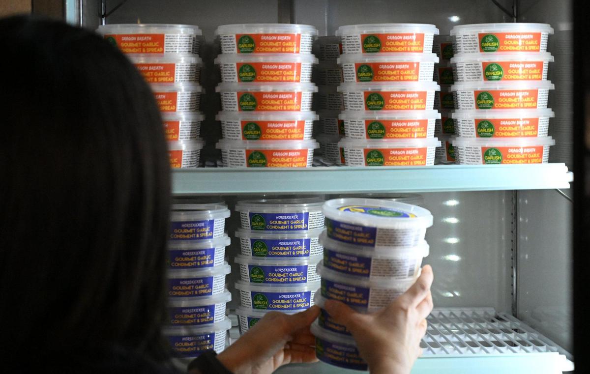 Karla Lugo stocks the shelves with Garlish, the freshly made condiment and spread featuring garlic, available at Garlishious Deli on Fresno Street just north of Fresno City Hall. The deli offers sandwiches, pizza and salads with Garlish spread in various flavors and more. Photographed Thursday, Oct. 19, 2023 in Fresno.