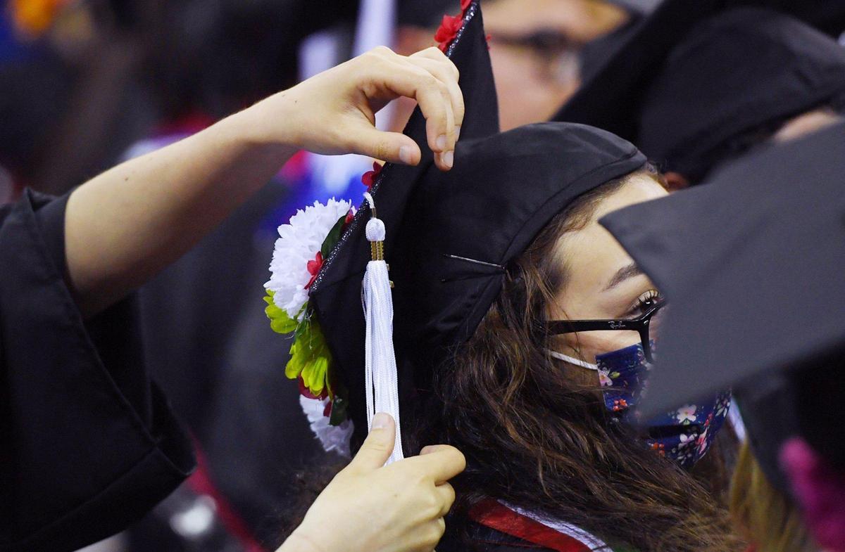 A student receives help with her cap at Fresno State’s College of Arts and Humanities commencement exercise Friday, May 20, 2022 in Fresno.