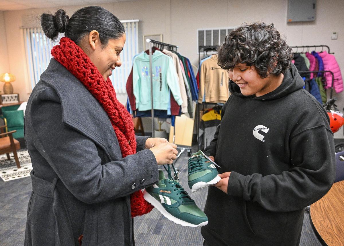 Emma Chavez, a community school coordinator at Jackson Elementary School in Fresno, helps Giovanni Ruiz Gonzalez with a new pair of shoes that were giving to him through the community school program on Wednesday, Dec. 18, 2024.