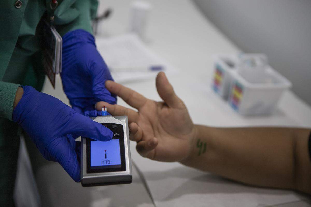 Dr. Navdeep Lehga checks a patient’s blood sugar in the exam room of the Saint Agnes Mobile Health Unit clinic, parked in the lot of Rojas Pierce Park in Mendota on Aug. 28, 2025. Photo by Larry Valenzuela, CalMatters/CatchLight Local