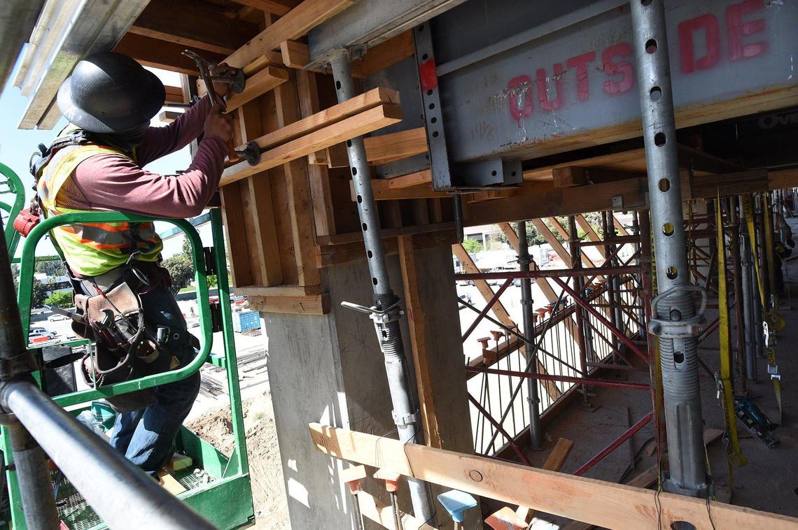 A construction worker hammers in a support during construction on the third floor of the Fresno Yosemite International Airport four-story garage, April 14, 2021.