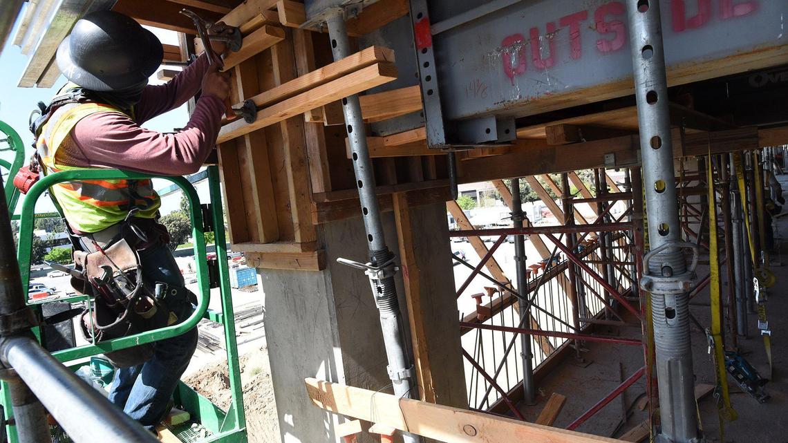 A construction worker hammers in a support during construction on the third floor of the Fresno Yosemite International Airport four-story garage, April 14, 2021.